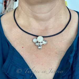 Buste d'une femme portant un collier avec un pendentif composé de petits disques concaves attachés les un aux autres en forme plus ou moins triangulaire. Une perle blanche est sur le disque supérieur.